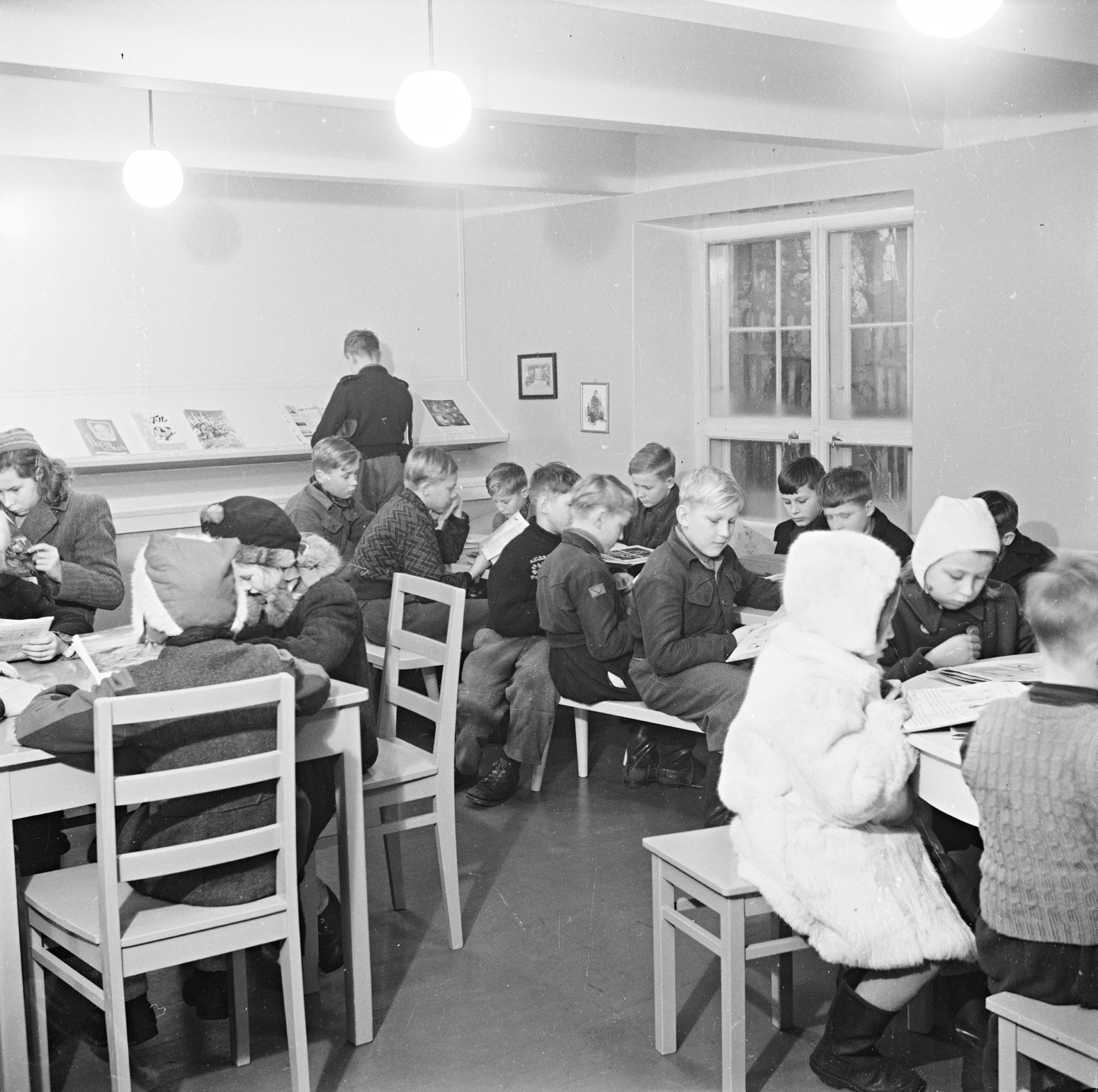 Mustavalkokuva lapsista lukemassa kirjastolla